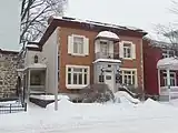 A small brick building with a side porch during winter