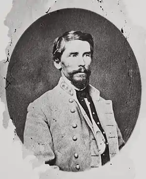 Oval black and white photo shows a bearded man wearing a gray military uniform with three stars on the collar.