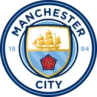 A rounded badge depicting a shield containing a ship, the Lancashire Rose, and the three rivers of Manchester.