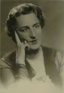 Black and white photograph of a middle-aged woman with short hair with her right hand resting on her face.