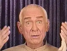 A wide-eyed man addressing a camera