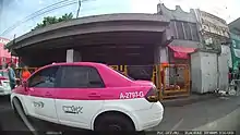 Image of a station entrance behind a taxi.