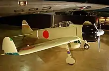 A propellor aircraft on display in a museum. The wing tips are folded up.