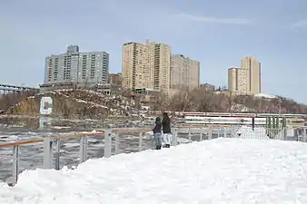 Boat dock and deck covered in snow, with Columbia "C" on opposite bank.