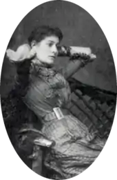 portrait of young white woman with dark hair, leaning back in a chair