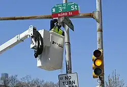 City worker installing a “N3RD St” sign at the intersection with Spring Garden Street