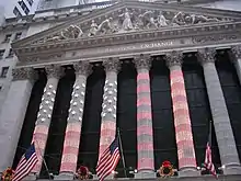  The columns of the NYSE lit up for Christmas, with the American flag being projected onto the colonnade