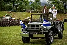 Nayib Bukele and René Merino Monroy riding in military vehicle while inspecting soldiers of the Salvadoran Armed Forces in 2019.