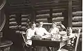 Photograph of three of Nevins Memorial Library's earliest librarians. Seated at the table in the Reference Room are: Miss Alice Chase, Miss Crosby and Miss Tooday Dorsey. Reference books are in the background and artifacts from the Nevins Historic Collection (Pheasant, Vase, Table and Richsonian Chair) are visible.