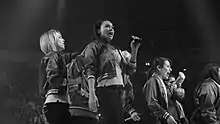 A group of female singers perform live on a stage.