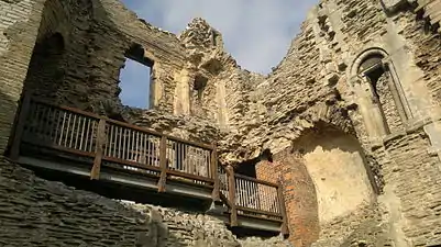 A ruined stone structure with a wooden walkway halfway up the wall.