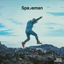 A man wearing a jean jumpsuit and dirty sneakers is jumping across a rock field against a blue sky. The album title appears above the man, with a crescent moon replacing the letter 'C', and the artist's name is on the bottom right corner.