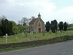 Small stone building with gravestones in the foreground.