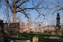 Photo from on top of a hill inside the cemetery showing some grave markers and the Youngstown city skyline