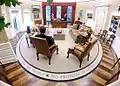 View from fireplace mantel: President Barack Obama from the back sitting near the fireplace with view toward desk, Rose Garden doorway at left, private study door ajar at right, and door to his secretary's office ajar at far left.