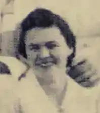 A smiling young white woman, with dark hair, wearing a white uniform