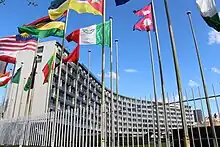 Grey building with country flags in front of it. Blue sky in the background.