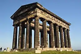 A monument in the style of a Greek temple, made of blackened stone