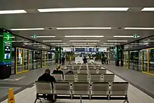 Underground waiting area surrounded by glass windows into the busway