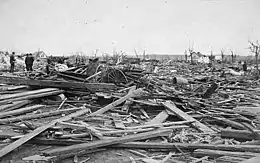 Black-and-white photograph highlighting wreckage and wooden boards