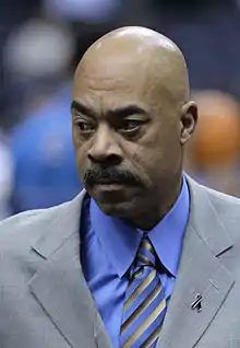 Headshot of a man, who wears grey suit, a blue shirt and a blue tie