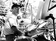 A black-and-white picture of a man sitting at a drum kit