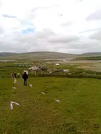 Marked walkway across a meadow, with large tents in the background