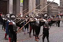 First rank holding pikes at charge for combat and second rank holding pikes at port to avoid injuring front rank soldiers while waiting to replace them (in real combat first 3–5 ranks would hold their pikes at charge, depending on the formation density and pole length, so as all the charged pikes would have their points in front, not inside the formation)