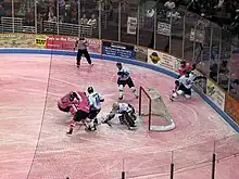 South Carolina Stingrays (in pink jerseys) battle the Toledo Walleye (in white jerseys) for control of the puck in front of the Walleye goaltender. The ice is dyed pink for Pink in the Rink 2010.