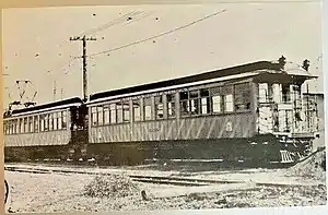 Two electric railway cars, one with a pantograph, at the end of a track