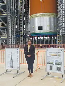 Photograph of Valerino smiling standing at the site of the Space Launch System program