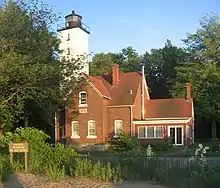 A brick house with a white, square lighthouse tower attached to the house.