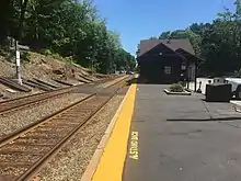 A low-level railway platform with a station building in the background