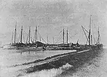 monochrome photograph of seaside quay with many fishing boats tied up