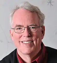 Head of man with white hair and glasses