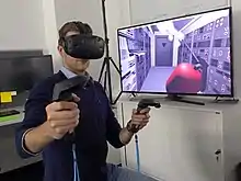 Image 6Researchers with the European Space Agency in Darmstadt, Germany, equipped with a VR headset and motion controllers, demonstrating how astronauts might use virtual reality in the future to train to extinguish a fire inside a lunar habitat (from Virtual reality)