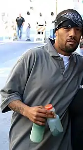 A man dressed in a grey shirt and black bandanna.