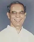 Smiling, bespectacled priest in white