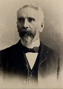 A black-and-white photograph of a man in a suit with a bow tie