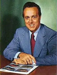 Man in a suit looking at camera while sitting at a desk