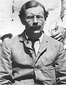 Photograph of a middle-aged man, wearing glasses, in a formal suit.