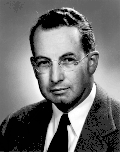 Head and shoulders of a man in suit and tie with glasses