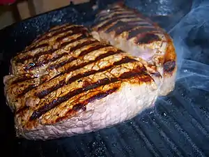 A rump steak cooking in a griddle pan