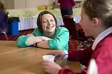 A photograph of Holland at a table smiling at a young person