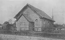 Black and white photo of a simple brick church building.