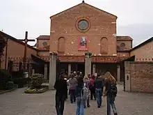 A group of individuals gracefully moves towards the entrance of The Sanctuary of the Leopoldo Mandic compound.