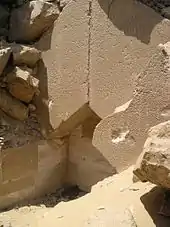 Two huge limestone blocks forming a pented roof are exposed with piles of rubbles on top of them.