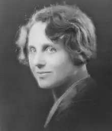 3/4 portrait of a short-haired woman wearing pearls and a dark blouse