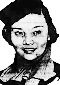 A young Asian woman wearing a box cap and a high-collared tailored jacket.