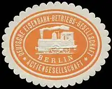 An orange and offwhite seal in the shape of an oval with an image of a train in the center with the word "Berlin" written under. Circled by the text of the German name of the company.